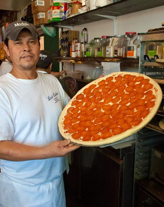 Jorge Resendiz with a large pepperoni pizza in the oven for baking, at Empire Slice House. mh