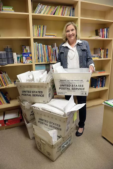 Cheri Fuller poses for a photo with boxes of letters and books to be sent to children of parents who are incarcerated at the Oklahoma Messages Project in Edmond, Wednesday, Dec. 7, 2016. - GARETT FISBECK