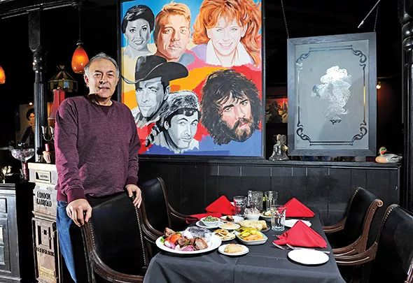 Jamil’s owner Greg Gawey stands next to one of the restaurant’s murals featuring famous Oklahomans. - GAZETTE / FILE