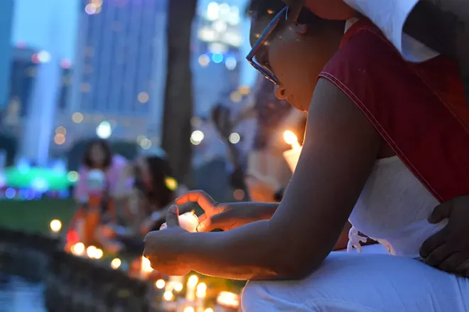 Lighting a candle at Lake Eola. - PHOTO BY MONIVETTE CORDEIRO