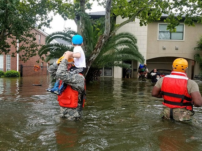 A Houston boy looks at his family Sunday as relief workers carry him to safety. - FLICKR/TEXAS MILITARY DEPARTMENT