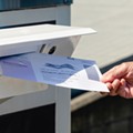 Poner una boleta de voto por correo en el buzón.
