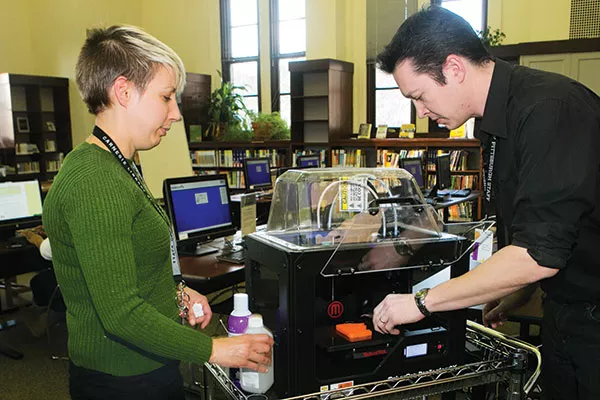 Hannah Schilperoort and Wes Roberts of the Carnegie Library use the facility's 3-D printer