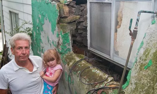 Jack Ingoldsby, with his granddaughter Abby, outside his Ivondale Street home, where the foundation has shifted due to landslides. - DAVID ROMAN