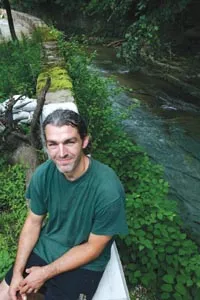 Millvaler Brian Wolovich stands beside a reinforced wall in his backyard. - HEATHER MULL