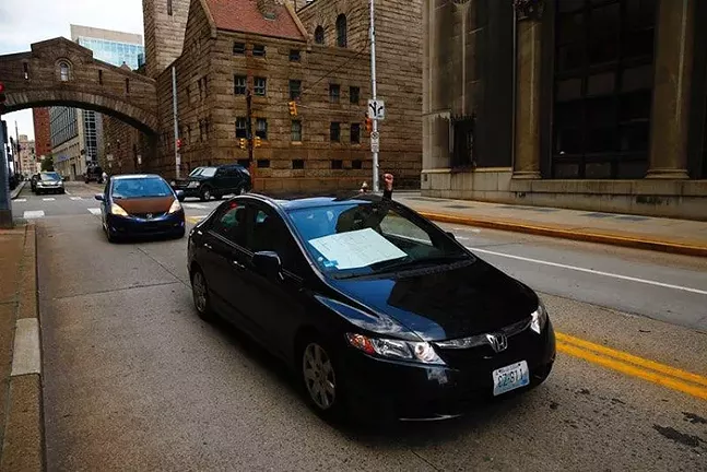 A car-only rally drives past the Allegheny County Jail in Downtown Pittsburgh. - CP PHOTO: JARED WICKERHAM