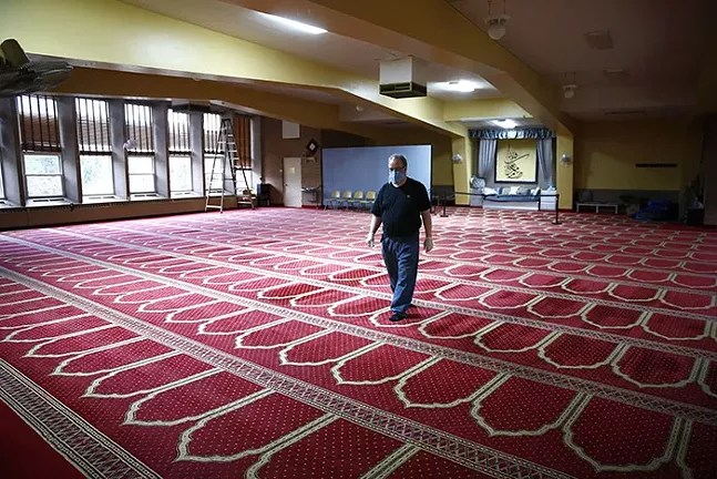 A volunteer walks through the large empty prayer room during Ramadan at the Islamic Center of Pittsburgh on Sun., May 3, 2020. - CP PHOTO: JARED WICKERHAM