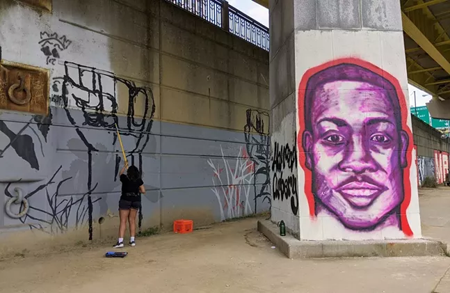 A volunteer paints near a portrait of Ahmaud Arbery under the Fort Duquesne Bridge, June 10, 2020. - CP PHOTO: AMANDA WALTZ