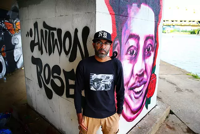 Pittsburgh Post-Gazette staff photographer Michael Santiago poses for a portrait in front of a Black Lives Matter mural with Antwon Rose painted behind him in Downtown Pittsburgh, along the Allegheny River, on Mon., June 15, 2020. - CP PHOTO: JARED WICKERHAM