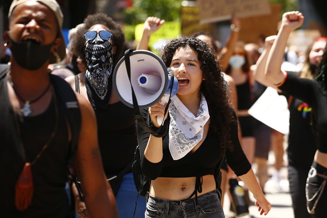 Leandra Mira shouts through a megaphone as she helps lead a youth-led march against police brutality and environmental racism in Downtown. - CP PHOTO: JARED WICKERHAM