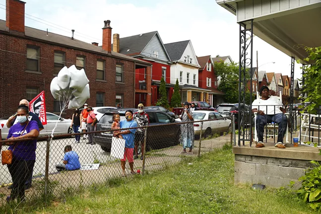 Residents of East Pittsburgh watch the presentation in honor of Antwon Rose II from their porches. - CP PHOTO: JARED WICKERHAM