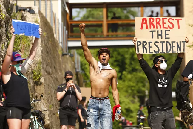 Anti-Trump protesters — including Pittsburgh political activist Prince Omowale, pictured in the center — demonstrate during a Trump boat rally that floated from the Hot Metal Bridge in the South Side to the North Shore on Sat., July 4, 2020. - CP PHOTO: JARED WICKERHAM