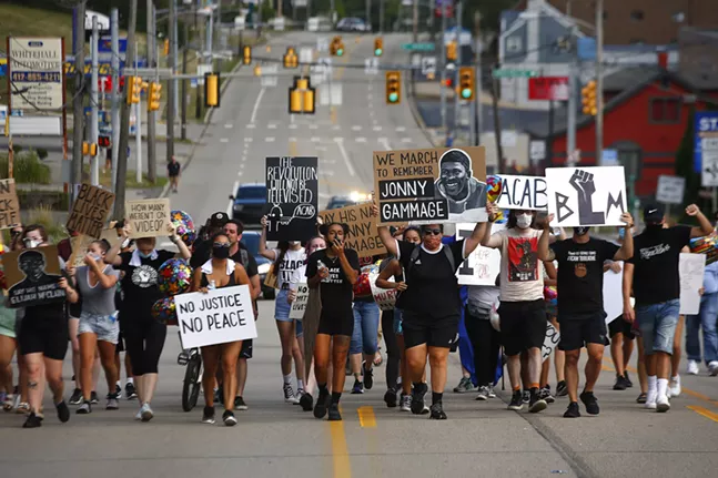 Protest organizer, Camille Redman, leads the group as they march through Brentwood from the Giant Eagle along Route 51 in honor of Jonny Gammage on his birthday. - CP PHOTO: JARED WICKERHAM