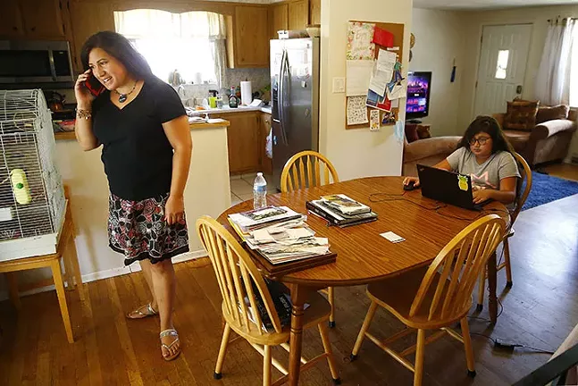 María Manautou Matos takes a phone call while her daughter Gabriella, 11, plays on the computer in their home in Allison Park. - CP PHOTO: JARED WICKERHAM