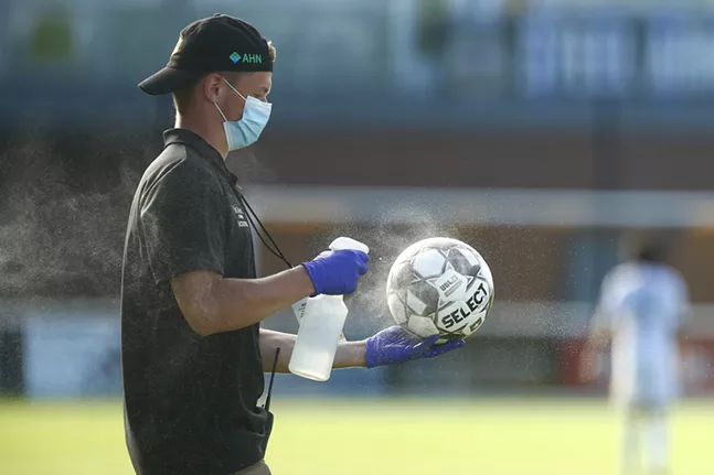 A Pittsburgh Riverhounds staff member disinfects a game ball in the first half. - CP PHOTO: JARED WICKERHAM