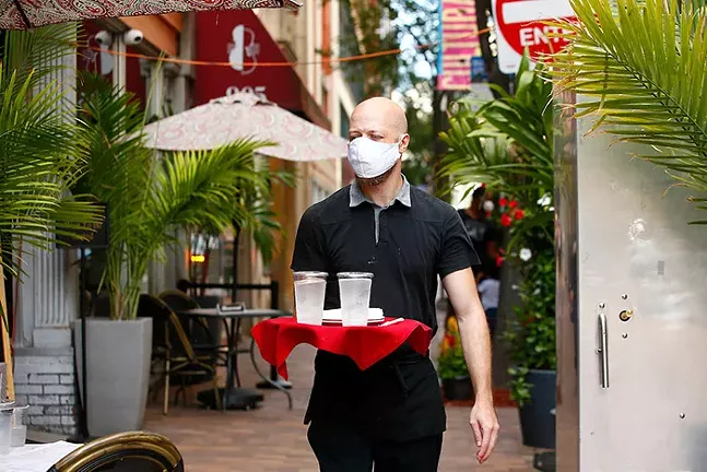 Coleman Bates, a waiter at Nicky's Thai in Downtown, delivers waters to a table outside on Fri., July 24. - CP PHOTO: JARED WICKERHAM