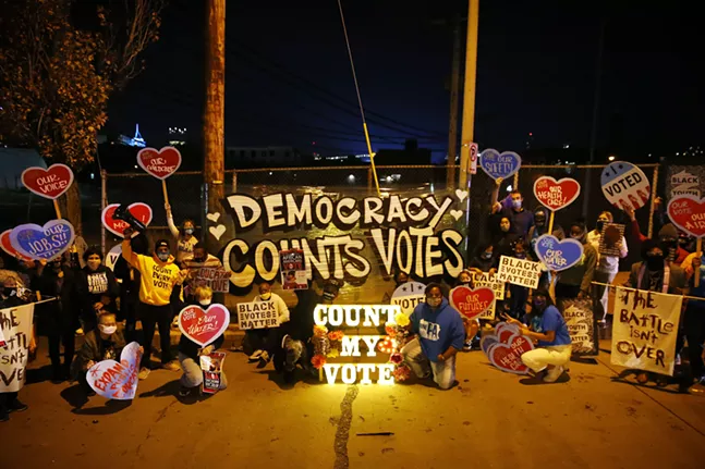 Organizers pose for a photo in front of one of many signs that lead the way to the Allegheny Elections warehouse in the North Side. - CP PHOTO: JARED WICKERHAM