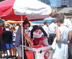 Todd Saulle, owner of The Pop Stop, and his employee, Mike Sestric, serve customers at the busy Farmers' Market in Market Square