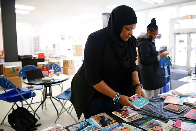 Thompson organizes books that will be included with care packages going out to residents. - CP PHOTO: JARED WICKERHAM