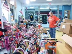Jimmy Cvetic looks at the piles of donated toys in the Global Glorious Productions Monroeville Mall Office. - PHOTO BY ASHLEY MURRAY