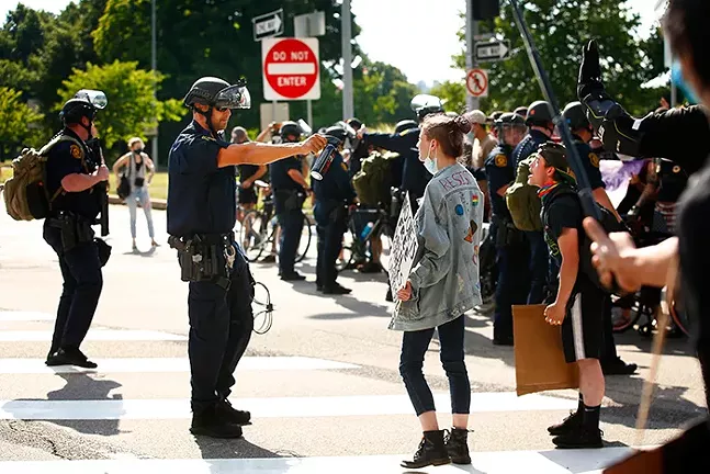 A Pittsburgh Police officer holds a pepper spray canister up to a protester in Downtown Pittsburgh on July 4, 2020 - CP PHOTO: JARED WICKERHAM