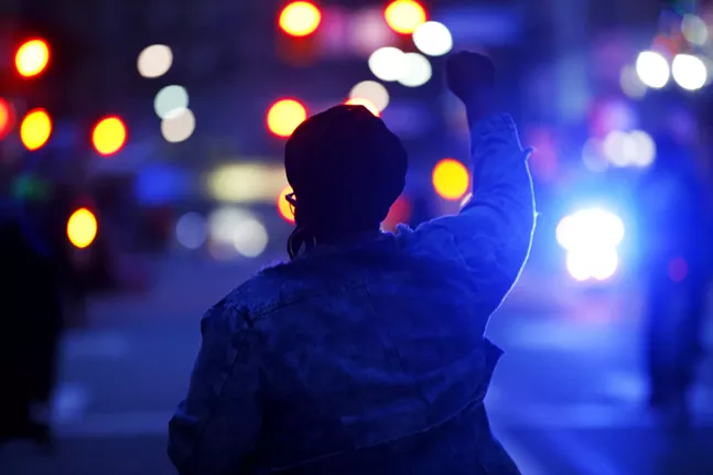 Jacquea Mae raises a fist and marches with protesters in front of a police motorcycle in Oakland. - CP PHOTO: JARED WICKERHAM
