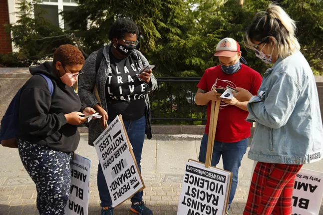 Protesters check their phones at Freedom Corner while the guilty verdict was announced against Derek Chauvin in the murder of George Floyd. - CP PHOTO: JARED WICKERHAM