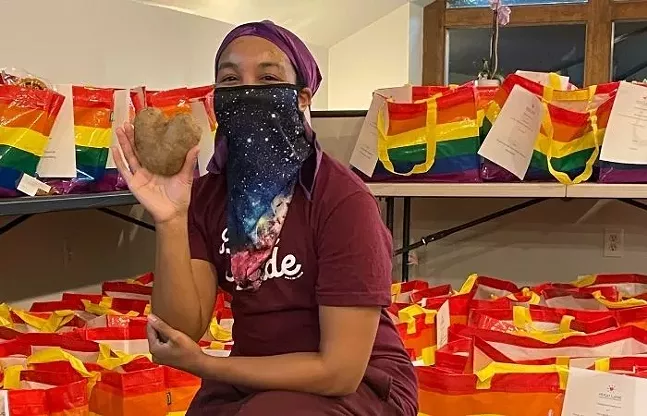 Hugh Lane Wellness Foundation program director Coley Alston poses with a heart-shaped potato in between packing Friendsgiving Rainbow Turkey Bags - PHOTO BY SARAH MILLER