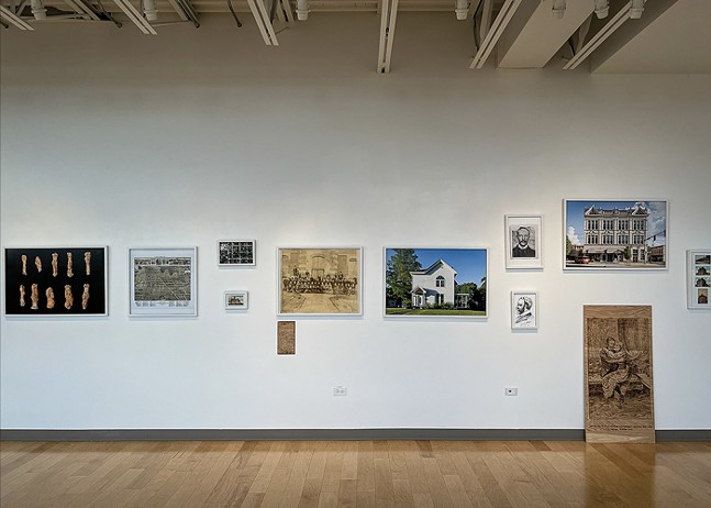 A series of photographs for the Pearl Bryan exhibition at Robert Morris University hang on a white wall.