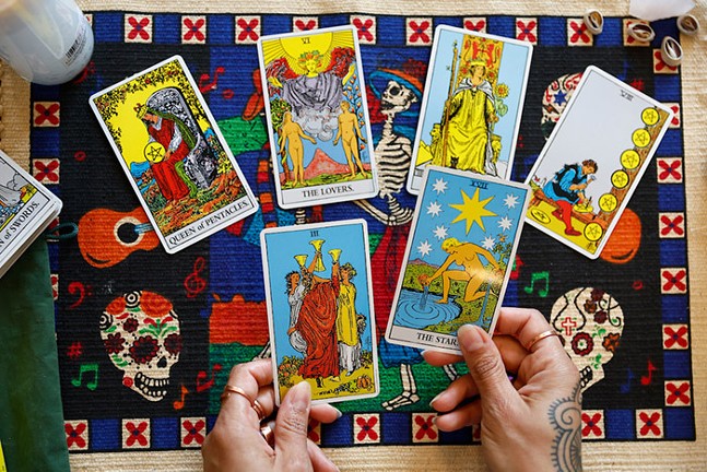 A tarot spread is laid out on a colorful table cover.