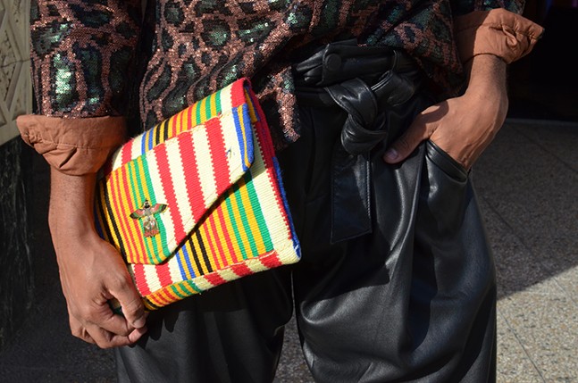 A close up of a man's hand holding a multicolored handbag