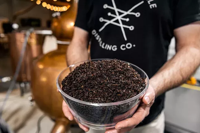 Close up of a bowl filled to the brim with dark brown dried tea leaves.