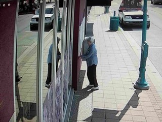 An unidentified woman affixes a sticker to the wall of Carnegie Stages, as seen on a security-camera image - PHOTO COURTESY OF CARNEGIE STAGES