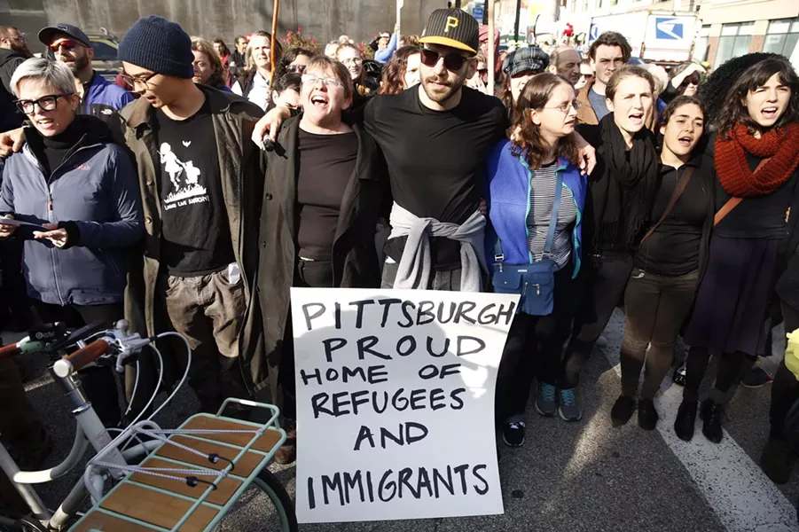 Marchers holding an immigrants rights sign during a rally for Tree of Life victims - CP PHOTO: JARED WICKERHAM
