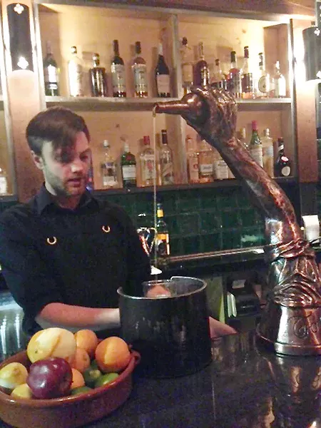 Zachary Maddox pours from the life-sized silver arm on Morcilla's bar top. - PHOTO BY CELINE ROBERTS