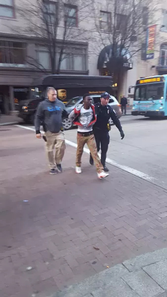 Abdulkadir Abdi being taken across the street from his bus stop on the north side of Liberty Avenue. - PHOTO BY REBECCA NUTTALL