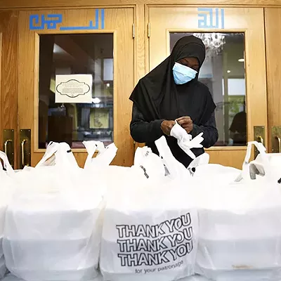 A volunteer puts on gloves before handing out Iftar boxes at the Islamic Center of Pittsburgh during Ramadan in May 2020, part of Alex Gordon's award-winning story on Pittsburgh's Muslim community celebrating Ramadan during the pandemic.