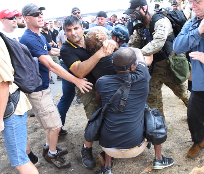 An alt-right Proud Boys member (dumb black golf shirt) slams a left-wing protester to the ground