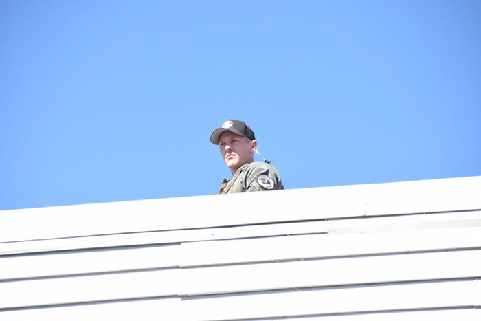 A Vancouver cop watches over protesters from the roof of a building