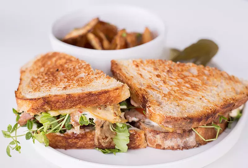 A porchetta sandwich is served on rustic bread with garlic-herb aioli-mustard and smoked cheese. - MABEL SUEN