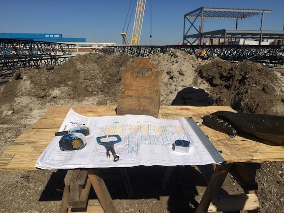 Blueprints and tools and stuff with the newly erected steel frame in the background. - MITCH RYALS