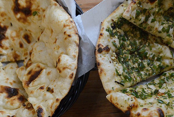 Naan dough is placed in a tandoor oven, giving it a distinct flavor. - TOM HELLAUER