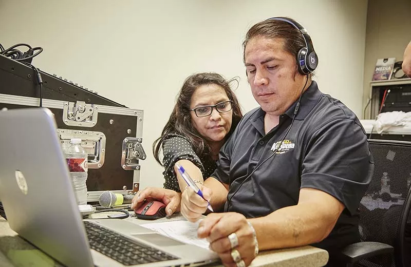 La Ke Buena owner Brenda Garcia works with her sound engineer during the broadcast. - PHOTO BY STEVE TRUESDELL