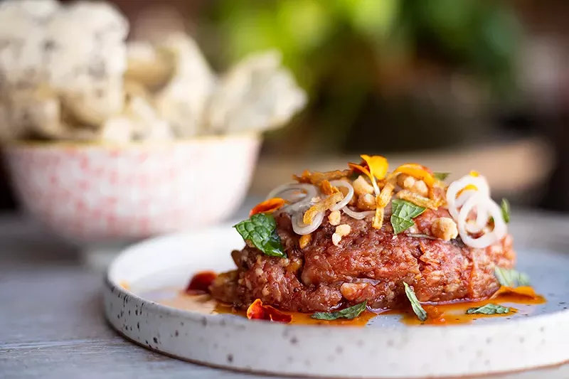 Spicy lamb tartare topped with fried shallots and candied pine nuts and served with a rice cracker. - MABEL SUEN