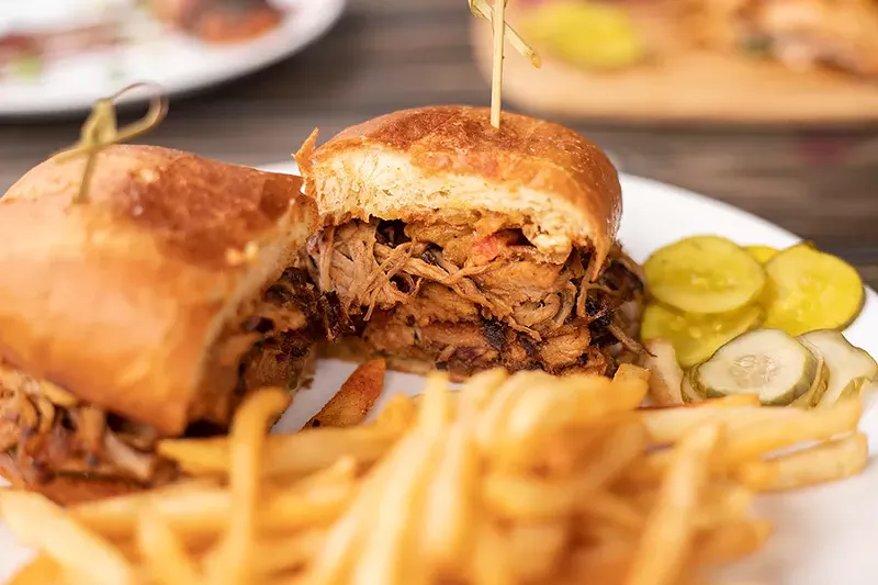 The loaded pulled pork sandwich stacks pulled pork, chicharrones, sweet pickles, Texas sauce and queso. - MABEL SUEN