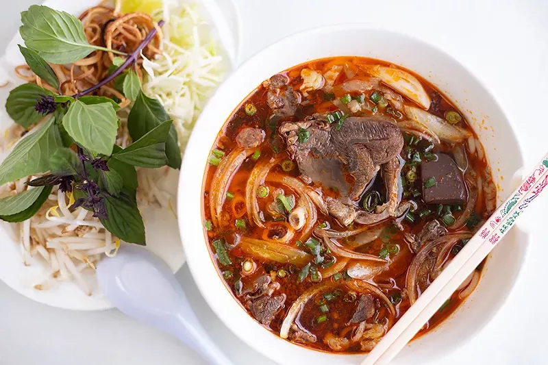 Bún bò huế with noodles, pork patty, pork feet and beef shank and a side of fresh herbs and bean sprouts to incorporate in the soup. - MABEL SUEN