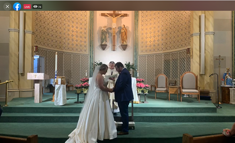 Katie and Zach Hawkins bow their heads in prayer as their priest marries them. The two hosted a Facebook live stream to celebrate their wedding during COVID-19. - SCREENGRAB FROM THE LIVE STREAM OF KATIE AND ZACH HAWKINS' WEDDING.