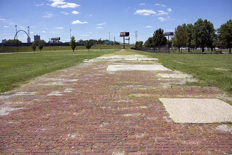 The remains of a century-old brick road runs partway through a grass field in East St. Louis. - PHOTO BY DANNY WICENTOWSKI