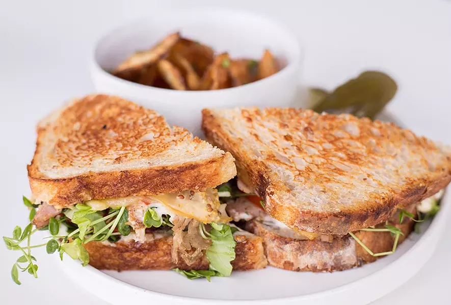 A porchetta sandwich is served on rustic bread with garlic-herb aioli-mustard and smoked cheese. - MABEL SUEN