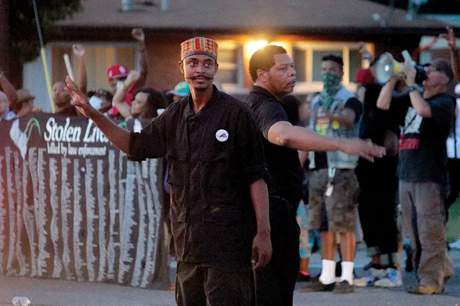In Ferguson, Davis and other New Black Panthers joined protesters just hours after Michael Brown’s death. In this image from August 14, 2014, Davis helps direct traffic during a demonstration. - DANNY WICENTOWSKI